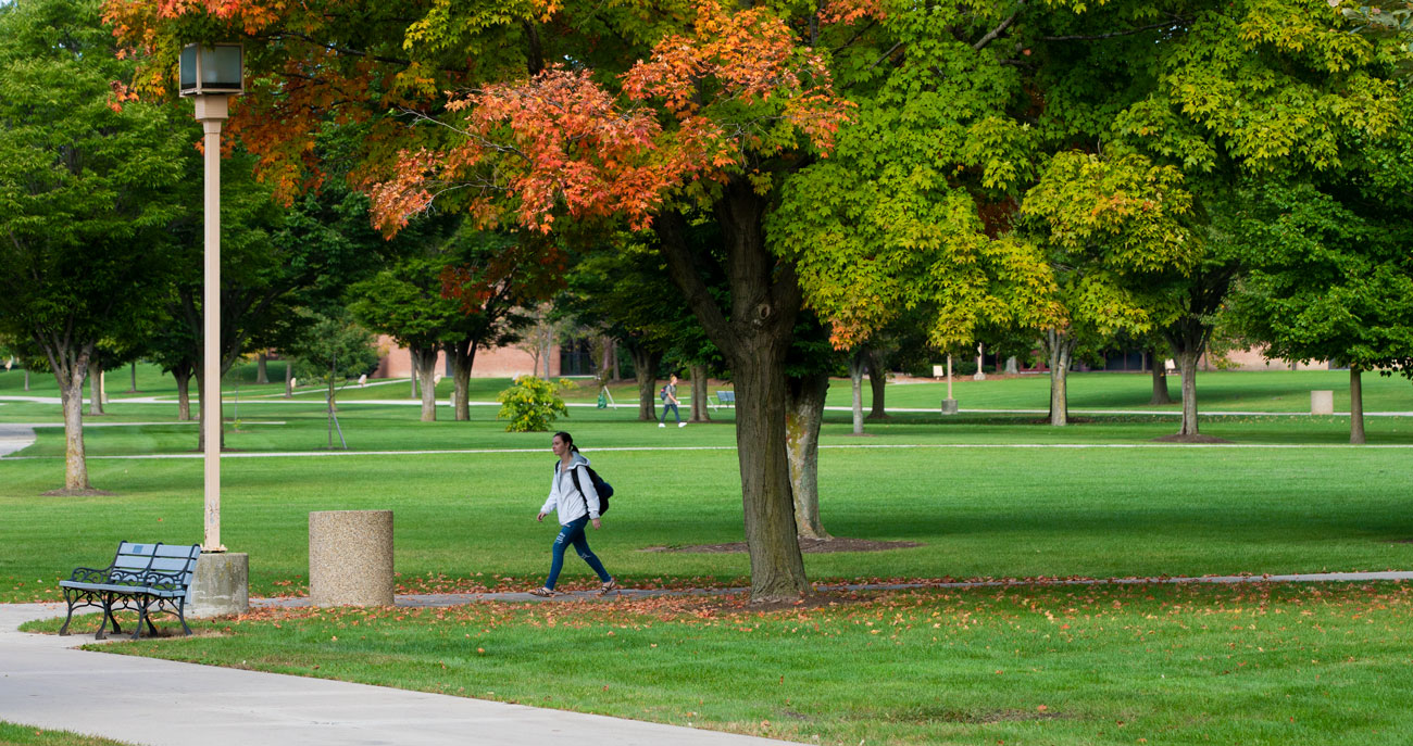 student walking across campus during the fall.