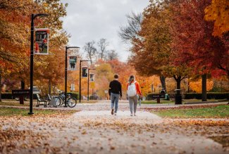 Students walking past fall leaves on Ohio Northern University's campus.